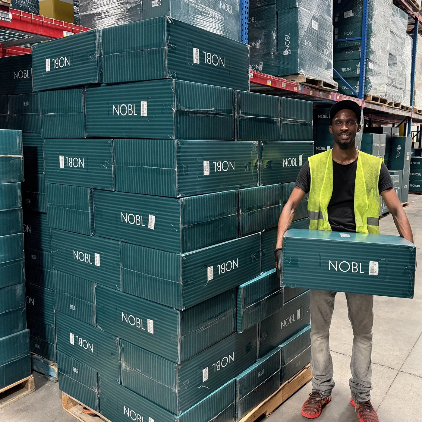 NOBL warehouse team member holding a product box among stocked NOBL inventory