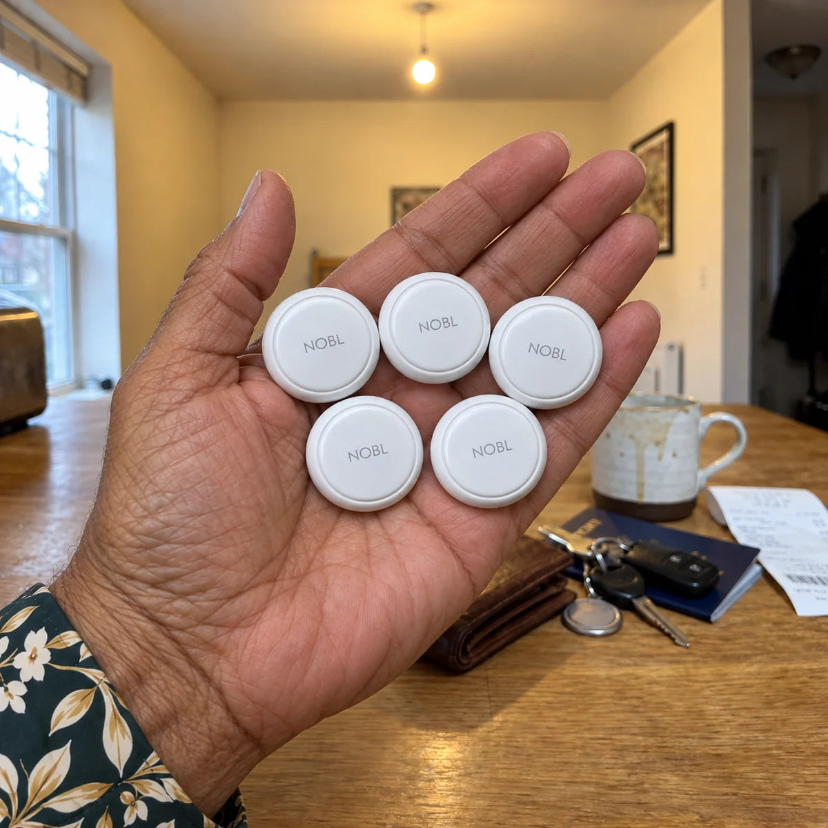 Five white NOBL Air™ trackers held by an older Black woman