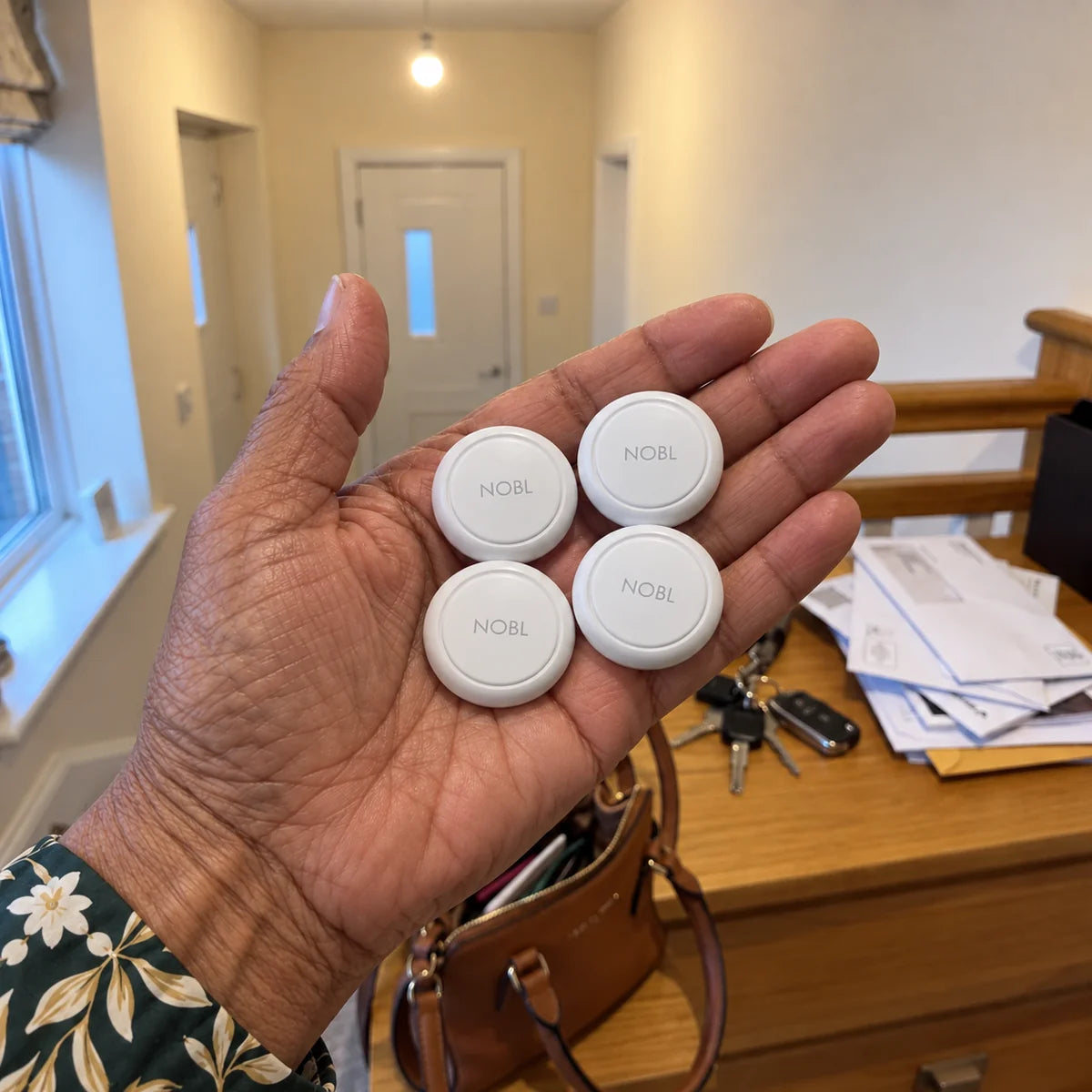 Four white NOBL Air™ trackers held by an older Black woman
