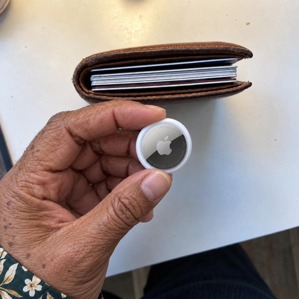 Apple AirTag held beside an open wallet