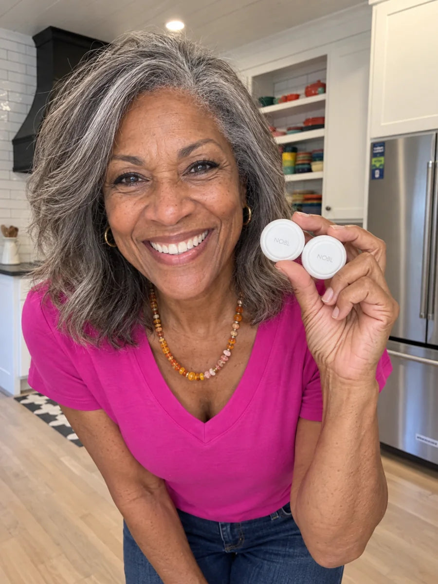 Mature Black woman holding two NOBL Air™ trackers at home