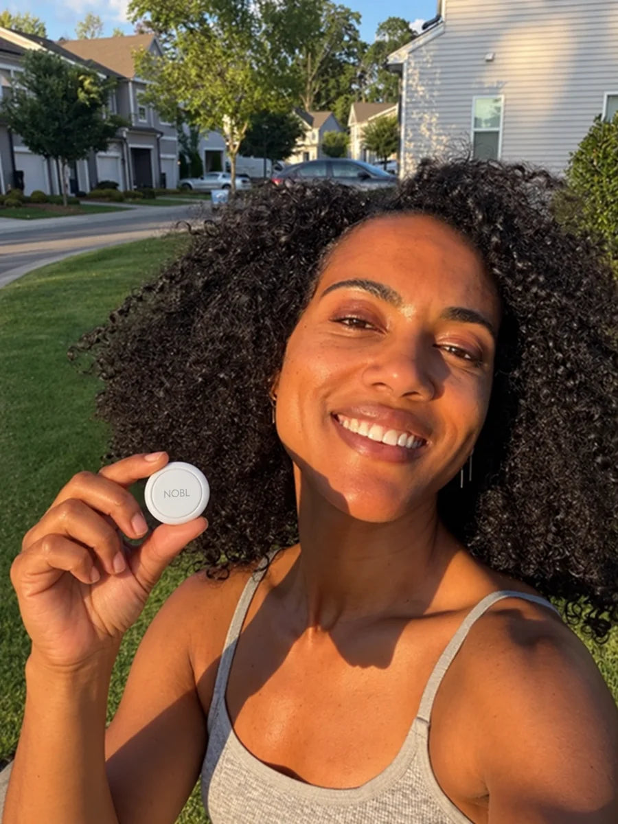 Black woman holding a NOBL Air™ tracker outdoors