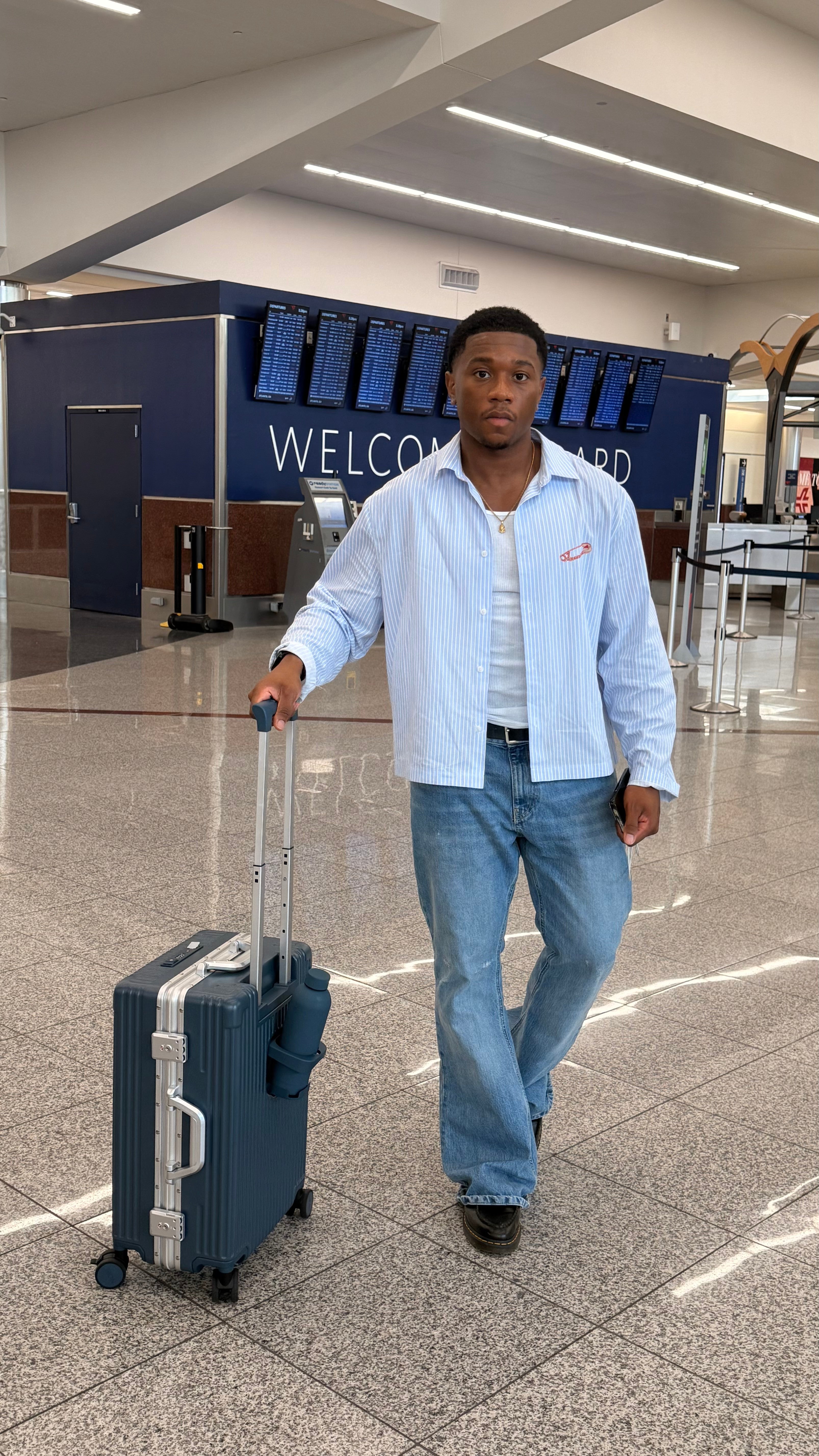 Traveler walking through the airport with a dark NOBL carry-on