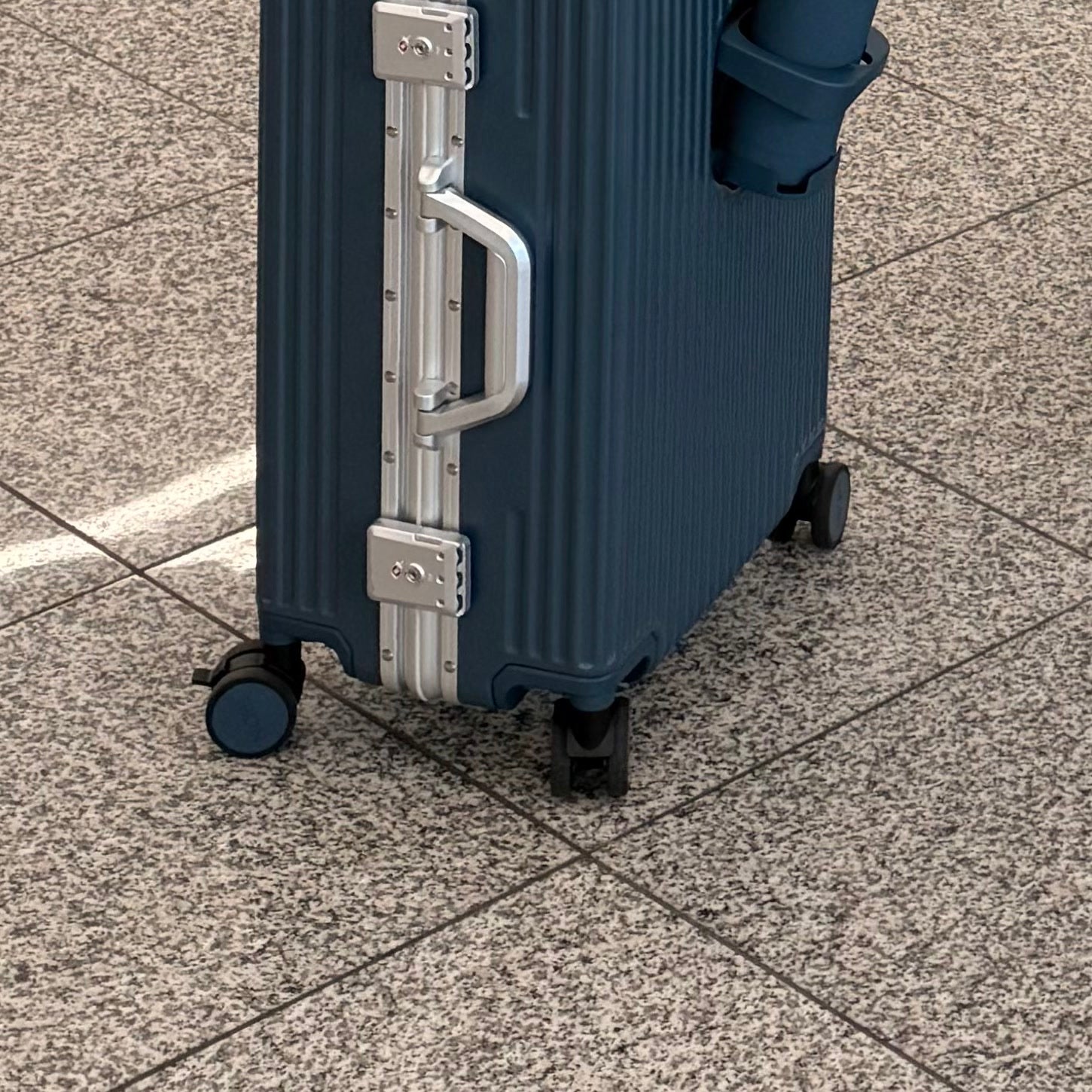 Close view of both TSA locks on a dark NOBL carry-on at the airport