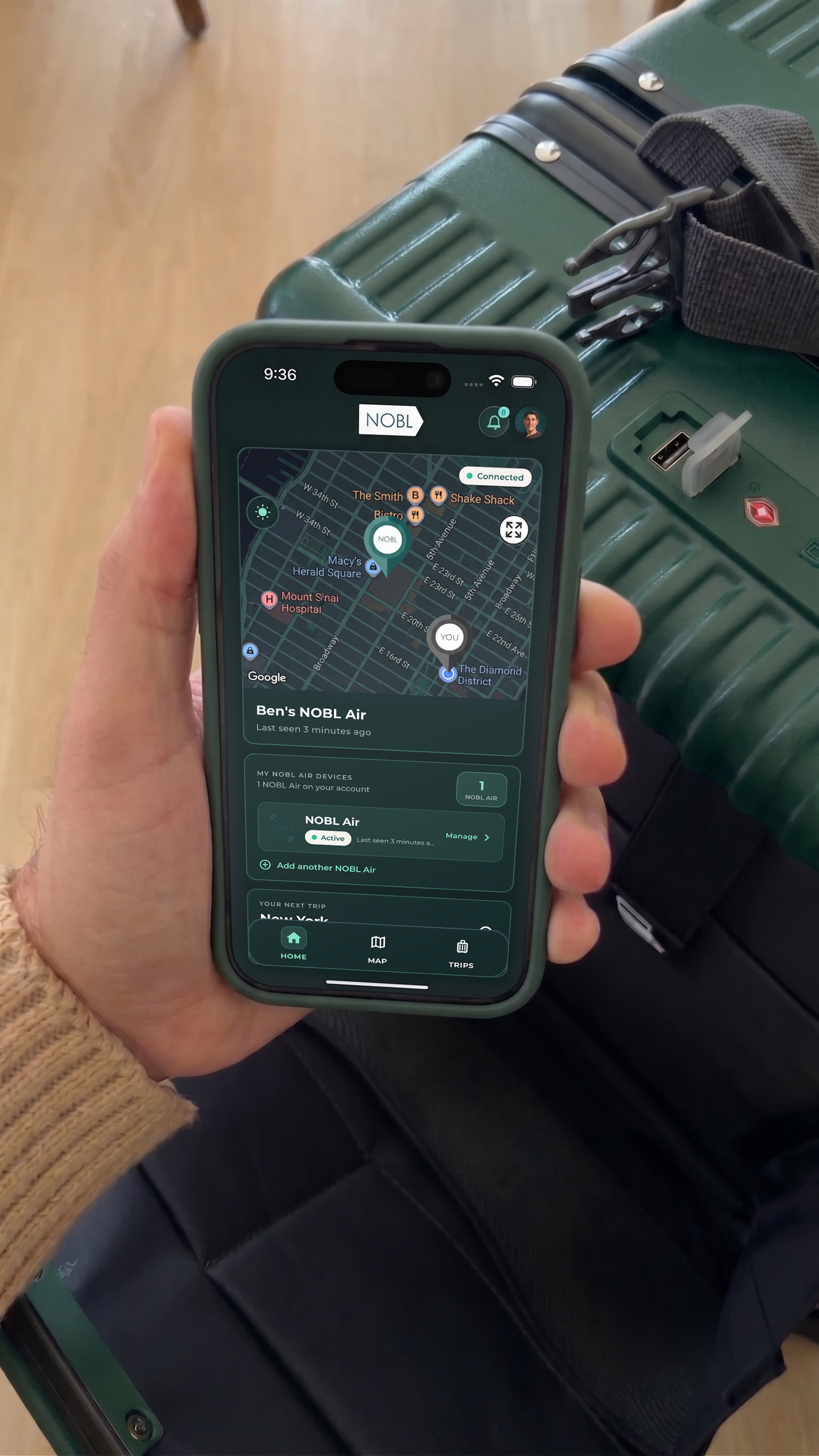NOBL Air app showing the suitcase location on a phone beside the NOBL carry-on
