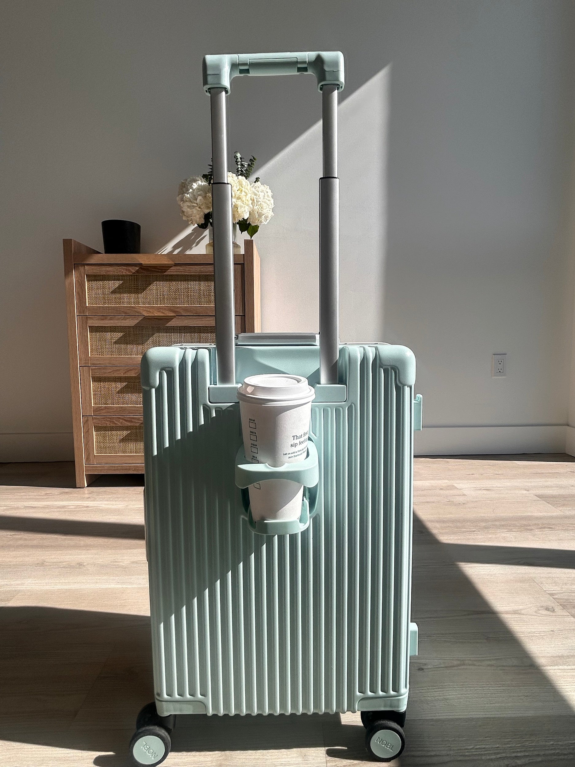 Mint NOBL carry-on with a coffee cup secured in the built-in cup holder