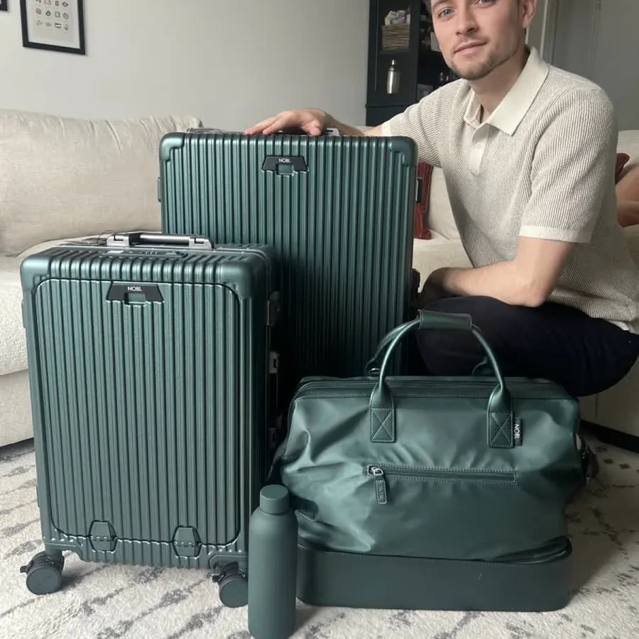 NOBL traveler with two hard-shell suitcases and a matching weekender