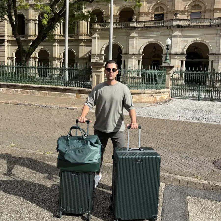 NOBL traveler outdoors with a carry-on, checked suitcase, and weekender