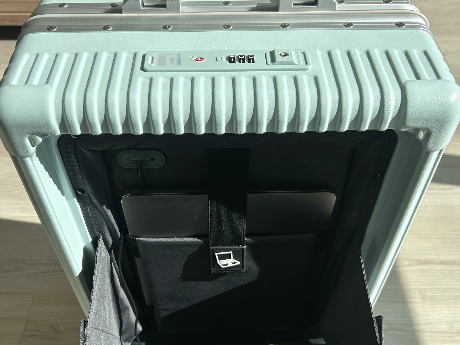 Split-screen comparison of a broken burgundy suitcase and an intact blue NOBL suitcase